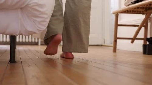 Barfota person går på trägolv med hälarna lyfta